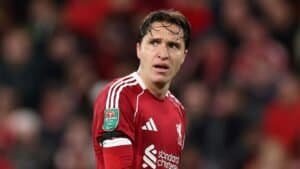 Liverpool-voetballer in actie tijdens een wedstrijd, gekleed in teamtenue en met aanvoerdersband.