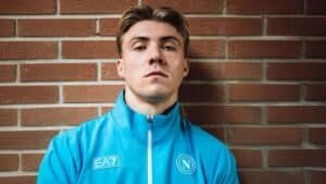 Jonge mannelijke atleet in blauw sportjasje voor een Marokkaanse bakstenen muur, Napoli voetbalteam, sportnieuws Marokko, Bladna News.