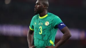 Joueur de football africain portant le maillot de l'équipe nationale du Maroc pendant un match.