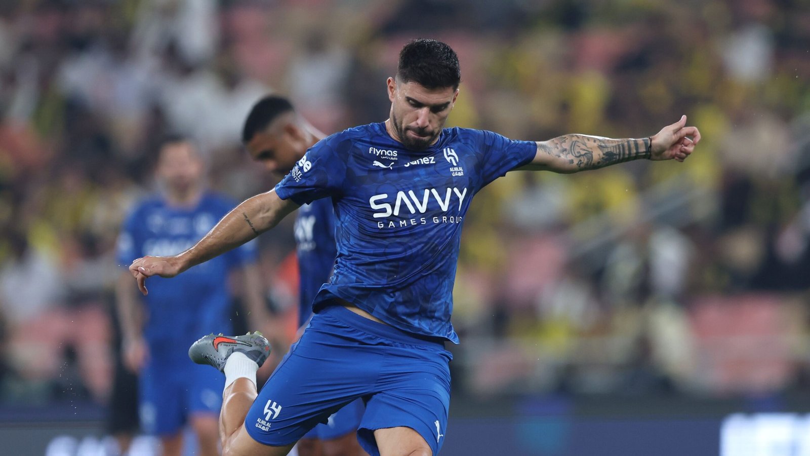 Athlete in blue jersey kicking soccer ball during match in Morocco.