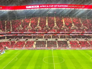 Vue du stade pendant la Coupe d'Afrique des Nations, montrant des sièges rouges et noirs vibrants remplis de supporters, prêts pour le match au Maroc.