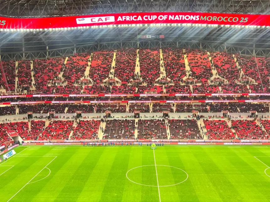 Vue du stade pendant la Coupe d'Afrique des Nations, montrant des sièges rouges et noirs vibrants remplis de supporters, prêts pour le match au Maroc.