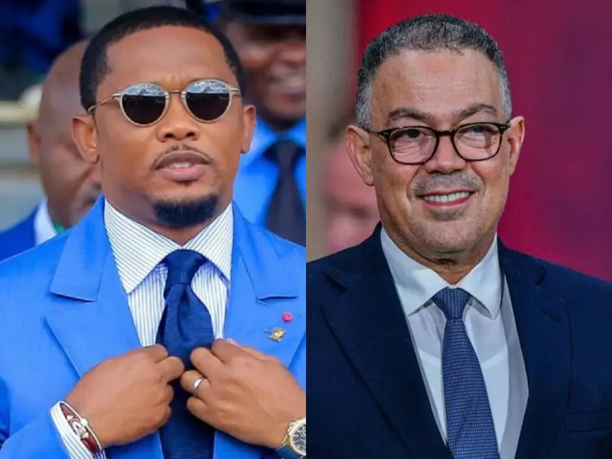 Samuel Eto'o en costume bleu ajustant sa cravate, aux côtés de Fouzi Lekjaa en costume sombre avec des lunettes, tous deux souriant sur un fond flou.