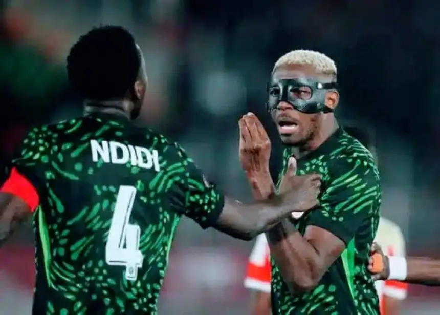Ndidi et un coéquipier masqué dans le kit vert vif du Nigeria célèbrent un but, montrant l'unité lors d'un match intense.