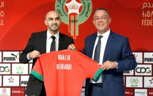 Houssain Amakran et Fouzi Lekjaa présentent le nouveau maillot de l'équipe nationale marocaine arborant le nom de l'entraîneur Walid Regragui lors d'une conférence de presse.
