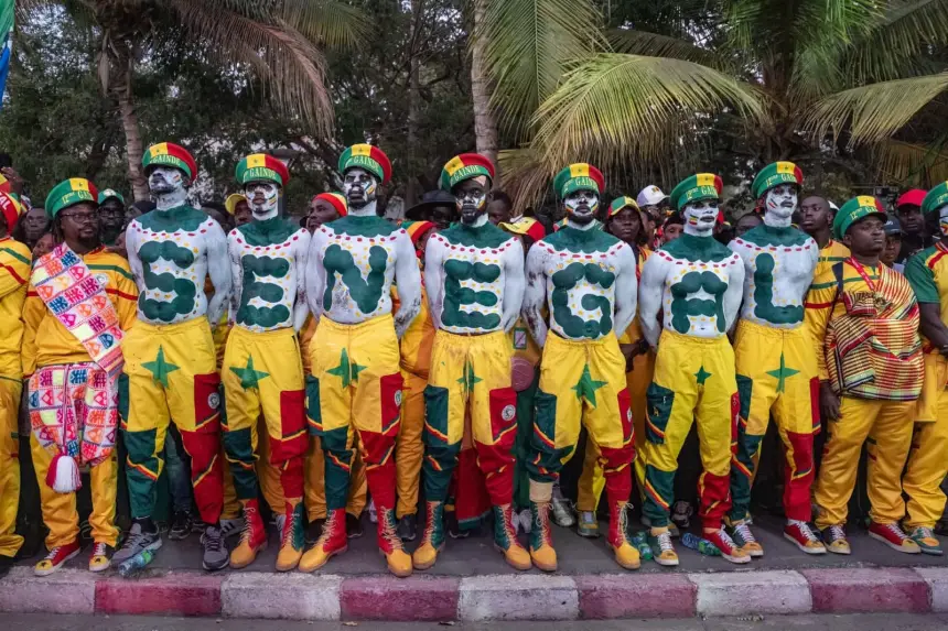 Des supporters sénégalais, vêtus d'atours festifs jaunes et verts, le corps peint formant le mot 'SENEGAL', unis dans la célébration avant un match de football.