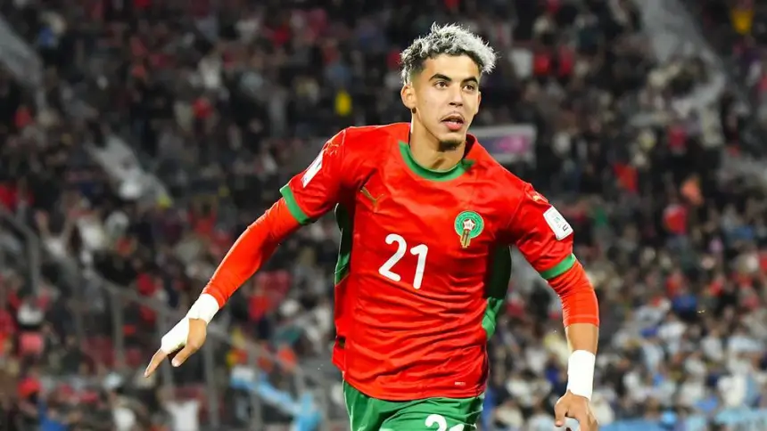Celebrating Moroccan player wearing a vibrant red kit with green accents, showcasing his joy after scoring during a match.