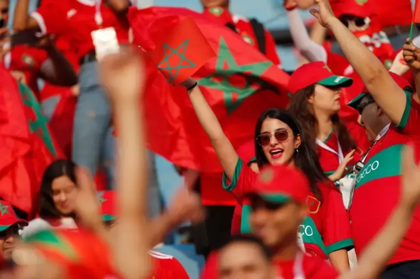 Les supporters marocains agitent des drapeaux et acclament en un vibrant rouge et vert, faisant montre d'une fierté nationale lors d'un match de football.