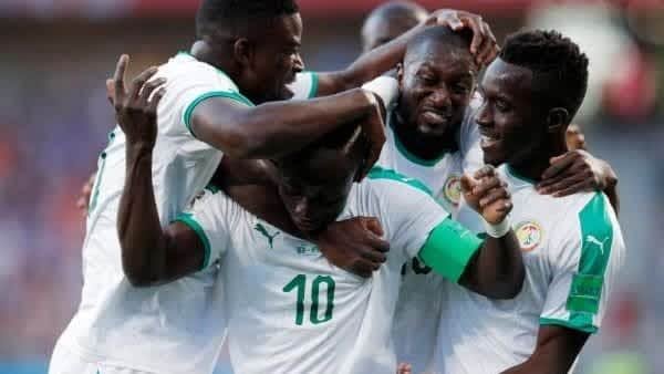 Les joueurs sénégalais célèbrent un but, s'embrassant dans leurs tenues vert et blanc, exprimant leur joie lors d'un match de Coupe du Monde.