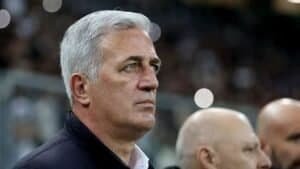 Vladimir Petkovic, aux cheveux gris et l'air sérieux, observe le match depuis la touche, avec les lumières floues du stade en arrière-plan.