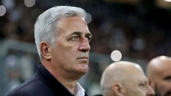 Vladimir Petkovic, aux cheveux gris et l'air sérieux, observe le match depuis la touche, avec les lumières floues du stade en arrière-plan.