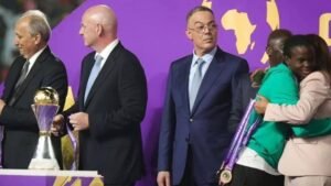 مسؤولو كرة القدم الأفارقة يقفون على المنصة، حاملين الكؤوس والميداليات، مع خلفيات أرجوانية وذهبية زاهية، احتفاءً بانتصار البطولة.