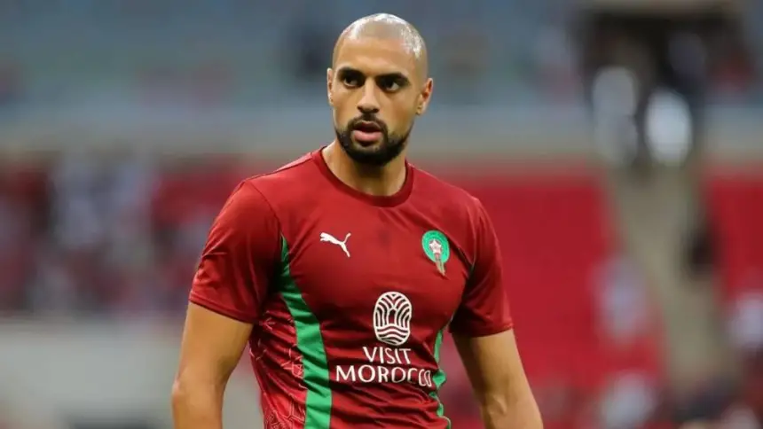 Moroccan football player in a maroon jersey with green accents, ready for action during a match, showcasing team pride and determination.