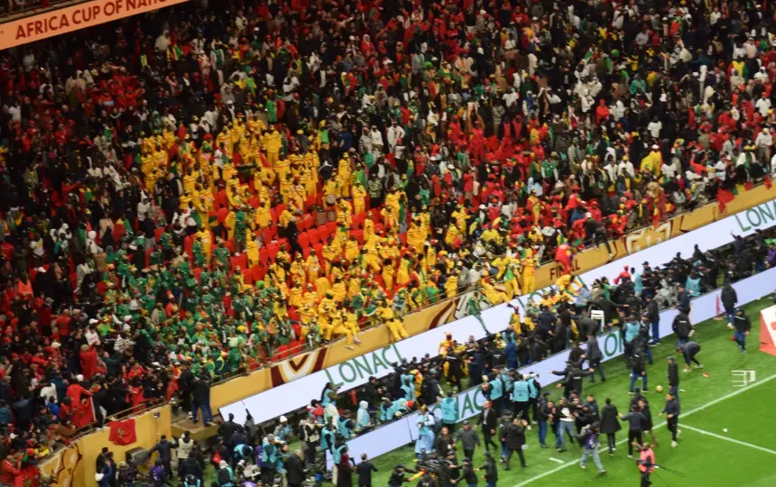 Vibrant stadium crowd celebrating at the Africa Cup of Nations, showcasing a mosaic of yellow, green, and red colours amid a lively atmosphere.