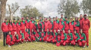 Moroccan players and staff pose in red and green tracksuits outdoors, showcasing national pride in a team gathering.