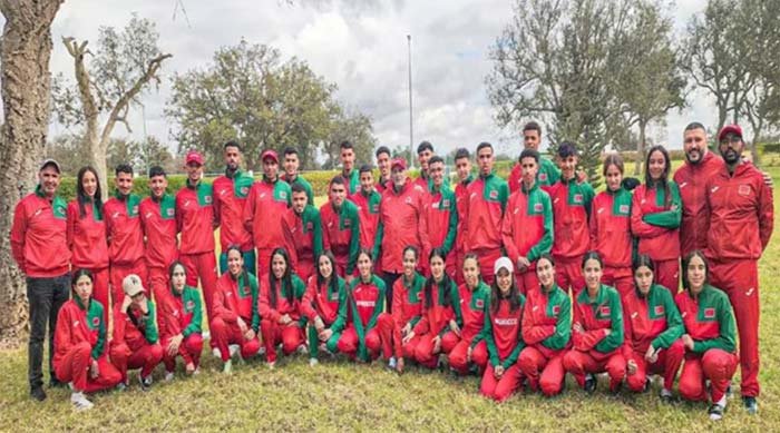 Moroccan players and staff pose in red and green tracksuits outdoors, showcasing national pride in a team gathering.