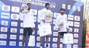 Winners of the 2026 International Semi-Marathon in Marrakech holding trophies, wearing race gear, with Volkswagen branding in the background.