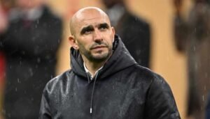 Walid Regragui, head coach of the Moroccan national football team, looks pensive in the rain, wearing a dark hoodie.