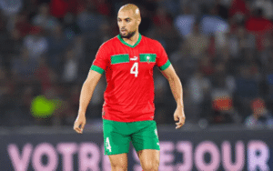Sofyan Amrabat in Morocco’s red kit with green accents, number 4 on his shirt, focused on the pitch during a match.