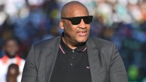 Événement d'actualité marocain mettant en vedette un homme en lunettes de soleil élégantes et en tenue formelle.