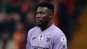 Andre Onana in een paars Trabzonspor-tenue; een geconcentreerde uitdrukking tijdens een wedstrijd, die zijn rol als prominent doelman benadrukt.
