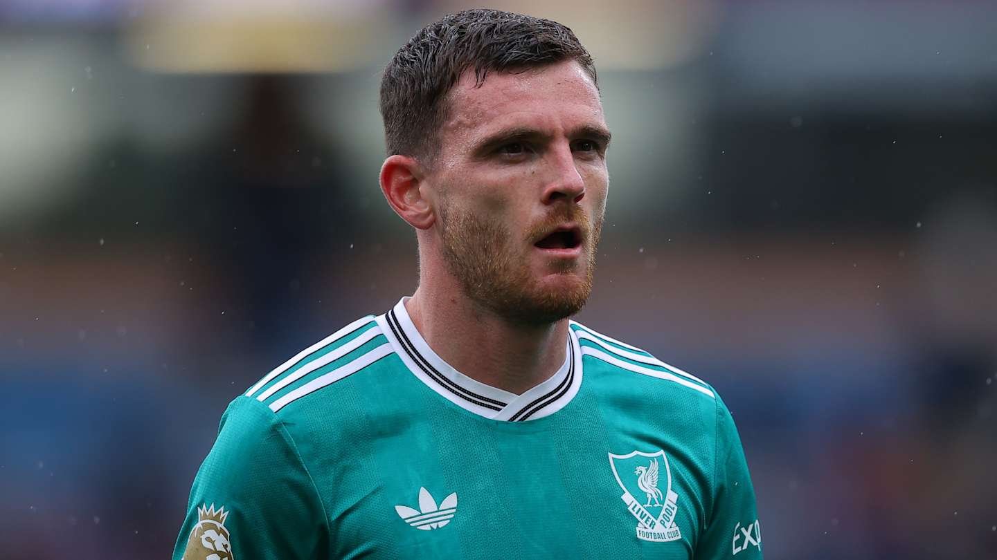 Andy Robertson in a teal Liverpool kit, focused and intense, during a match, capturing the anticipation of the game.