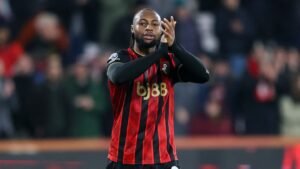 Antoine Semenyo applaudit les fans dans son kit de Bournemouth, aux rayures rouges et noires, lors d'une célébration de match à domicile.