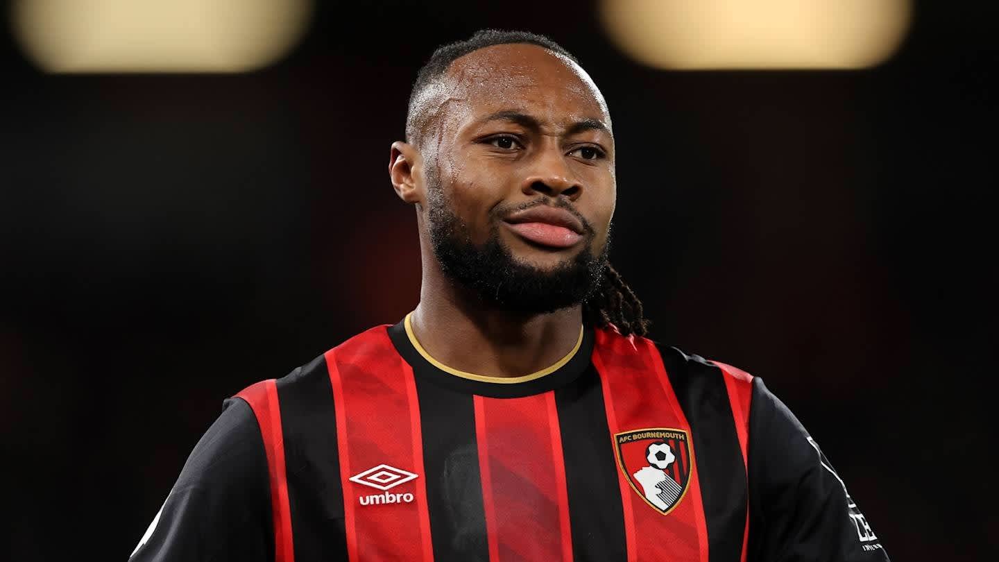 Antoine Semenyo, dans le kit rayé noir et rouge de l'AFC Bournemouth, se concentre avec une expression sérieuse lors d'un match.