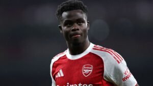 Bukayo Saka in het rood-witte tenue van Arsenal, geconcentreerd met uitgestoken tong, tijdens een wedstrijd in het Emirates Stadium.
