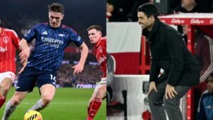Le joueur d'Arsenal, vêtu d'un maillot marine, défie un défenseur de Nottingham Forest en rouge, tandis que l'entraîneur Mikel Arteta observe attentivement depuis la touche.