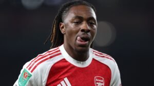 Eberechi Eze in het rood-witte tenue van Arsenal, met uitgestoken tong, tijdens een wedstrijd, waarbij het Carabao Cup-embleem zichtbaar is.