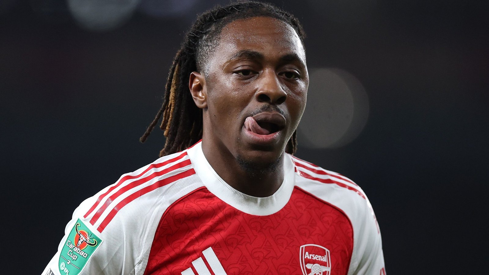 Eberechi Eze in het rood-witte tenue van Arsenal, met uitgestoken tong, tijdens een wedstrijd, waarbij het Carabao Cup-embleem zichtbaar is.
