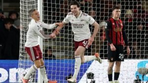Declan Rice viert een doelpunt met een teamgenoot tijdens Arsenal's wedstrijd tegen Bournemouth, terwijl een Bournemouth-speler toekijkt.