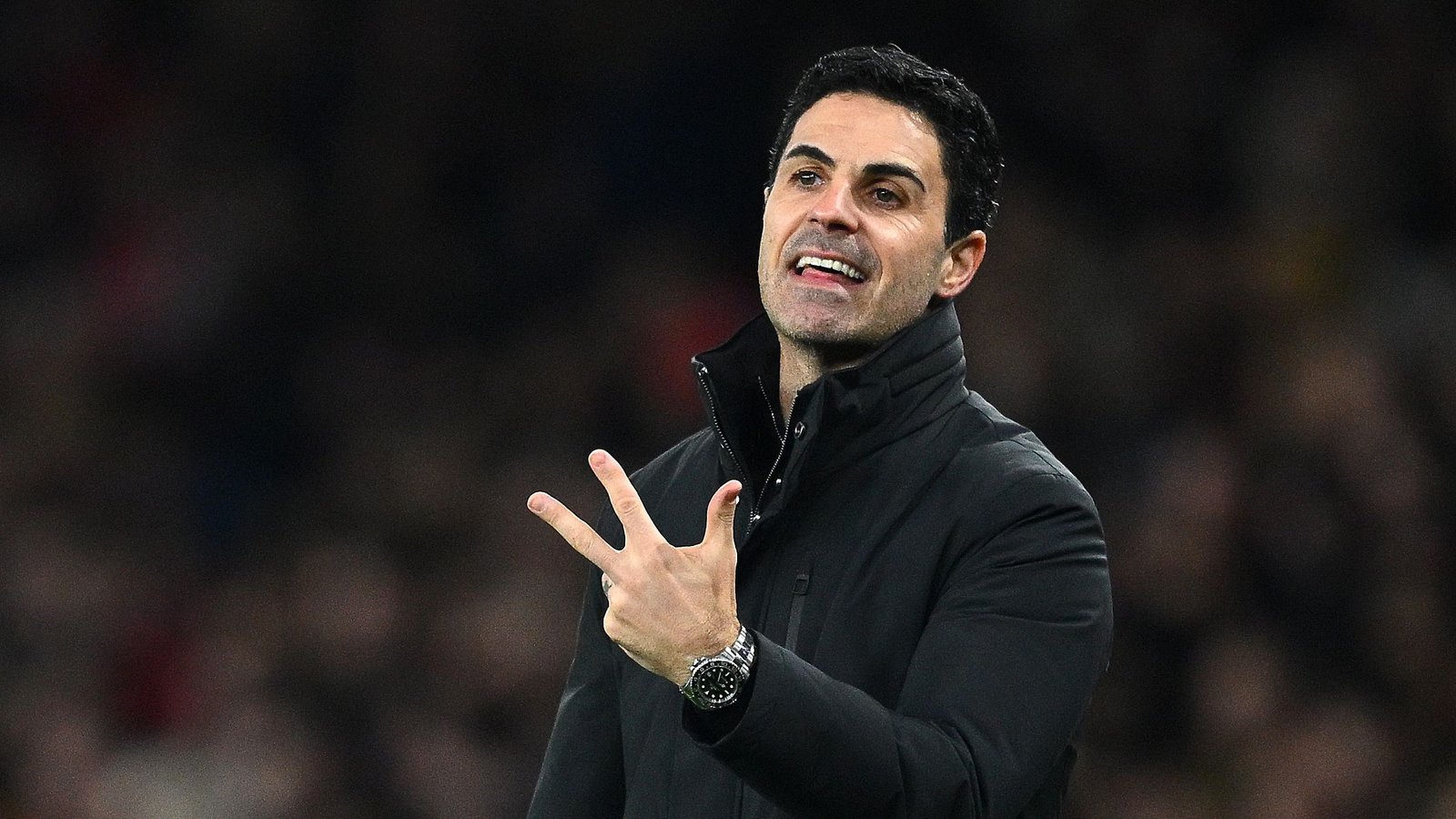 Mikel Arteta gebaart gepassioneerd aan de zijlijn tijdens een Premier League-wedstrijd, gekleed in een zwarte jas, wat zijn leiderschap voor Arsenal toont.