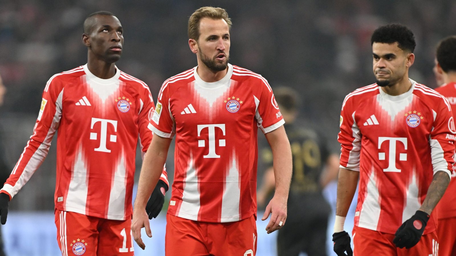 Bayern München-spelers, waaronder Harry Kane, tonen ontreddering na hun eerste competitienederlaag van het seizoen, gekleed in rode thuistenues.