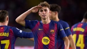 لاعب برشلونة يحيي الجماهير خلال مباراة وهو يرتدي الزي الأيقوني للأزرق القرمزي، مما يبرز موهبة لا ماسيا.