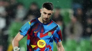 Barcelona-doelman Joan Garcia loopt van het veld in een kleurrijk tenue, terwijl regendruppels om hem heen vallen, wat een gespannen wedstrijdsfeer weerspiegelt.