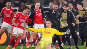 Benfica players celebrate jubilantly in the rain as goalkeeper Anatoliy Trubin celebrates scoring a last-minute header against Real Madrid.
