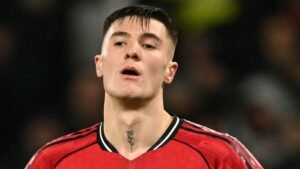Benjamin Sesko, en maillot rouge de Manchester United, l'air pensif avec un tatouage visible sur le cou, pendant un match.