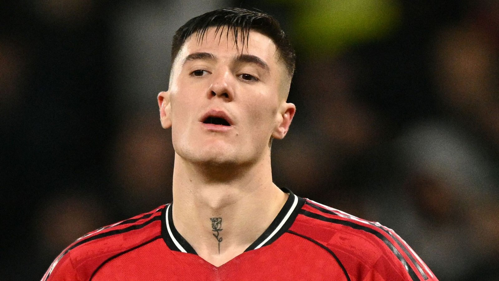 Benjamin Sesko, en maillot rouge de Manchester United, l'air pensif avec un tatouage visible sur le cou, pendant un match.