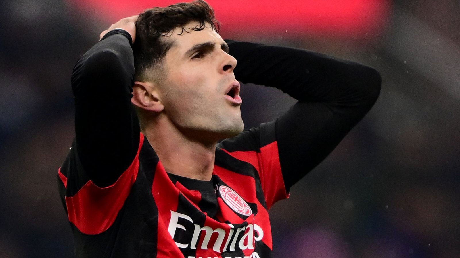 Christian Pulisic, in een rood-zwart tenue, toont frustratie tijdens een wedstrijd en houdt zijn hoofd in ongeloof.