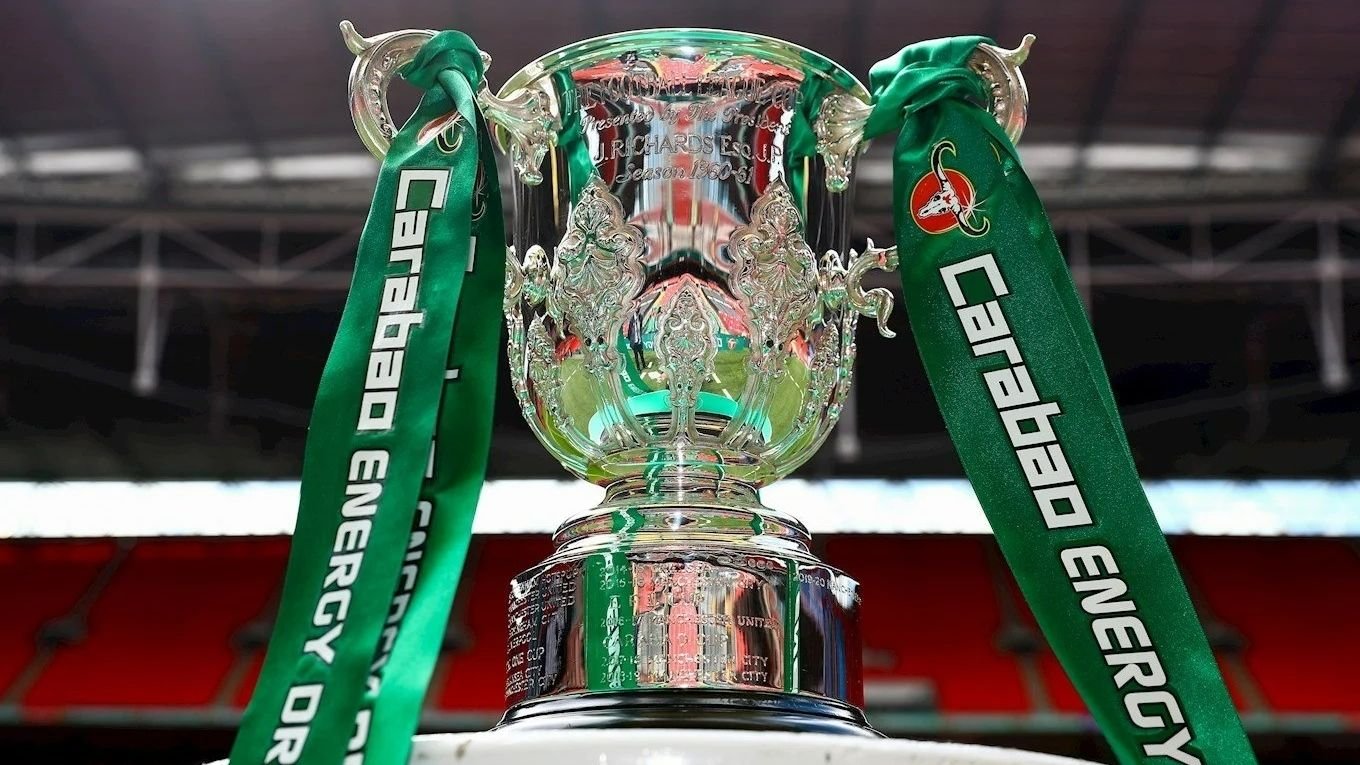Carabao Cup-trofee met zilveren details en groene linten, prominent tentoongesteld tegen een stadionachtergrond.