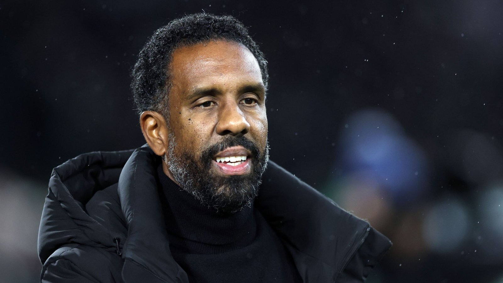 Wilfried Nancy, l'entraîneur au regard pensif, portant un manteau noir sur fond de stade flou, analyse la performance récente de son équipe.