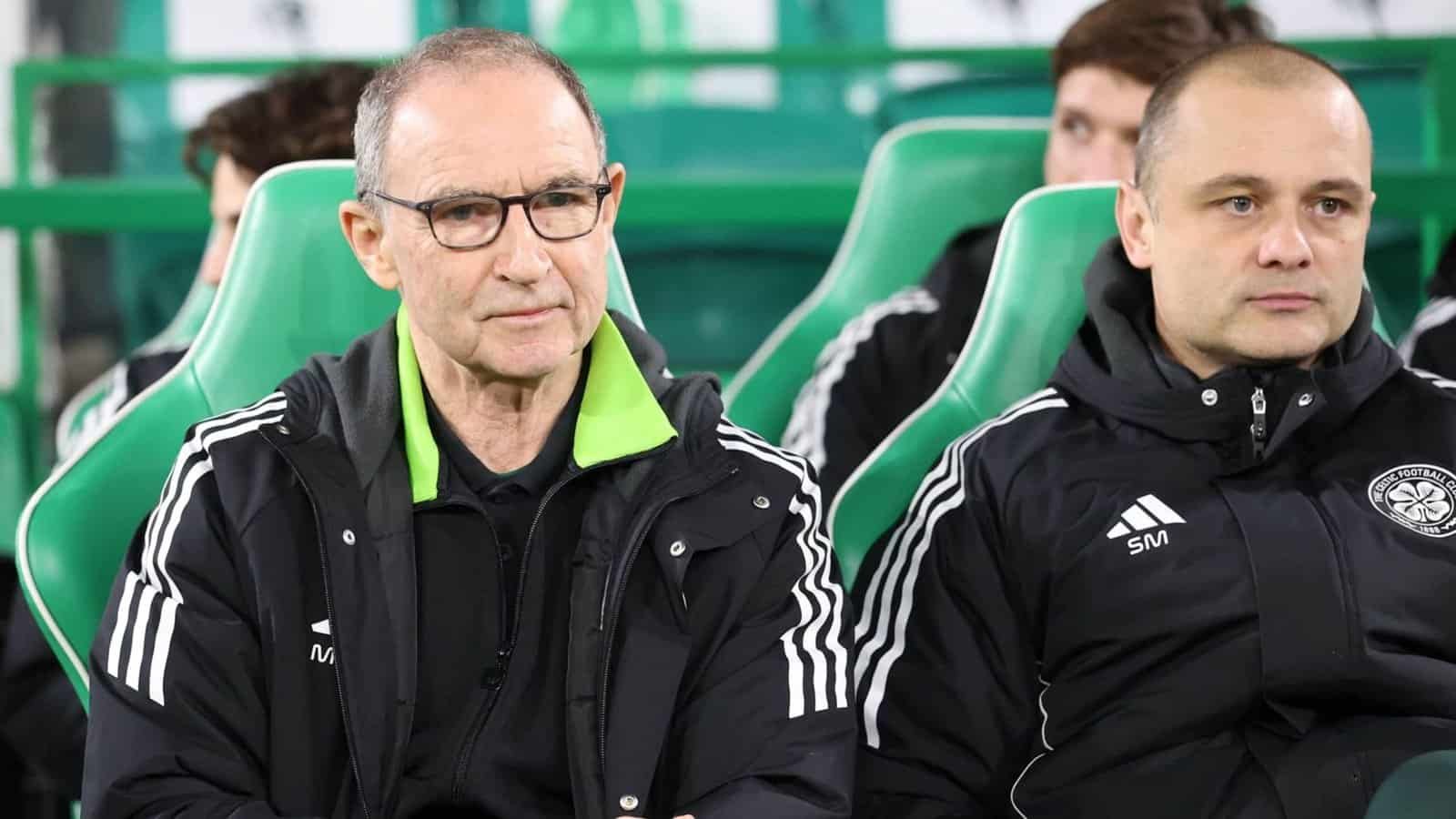 Martin O’Neill et son assistant sont assis sur le banc du Celtic, vêtus de vestes d’entraînement noires à bandes blanches, dans un stade de couleur verte.