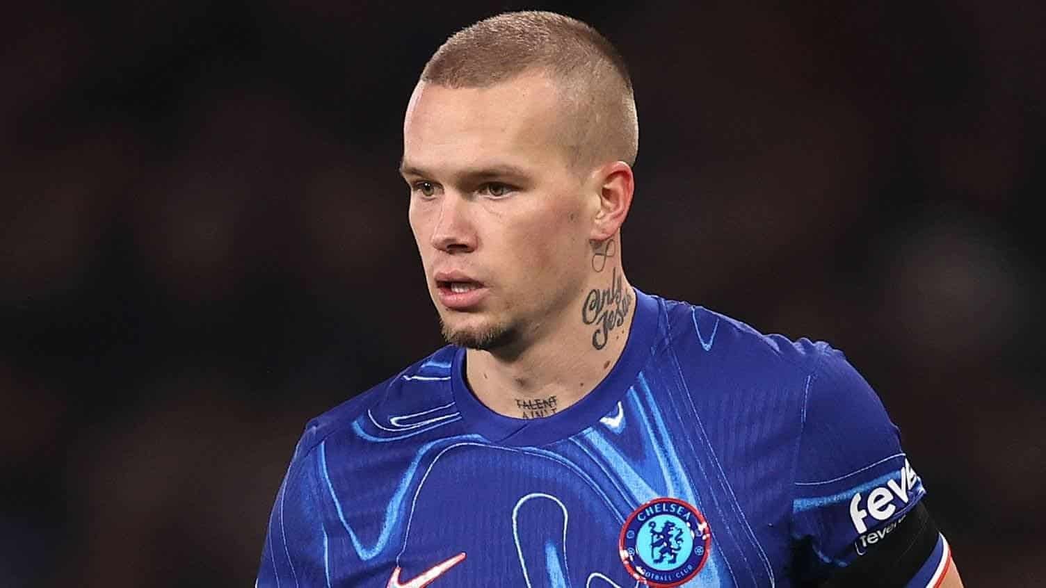 Chelsea-middenvelder Mykhailo Mudryk in het blauwe tenue van het team, waarbij hij zijn tattoo toont terwijl hij zich concentreert tijdens een wedstrijd.