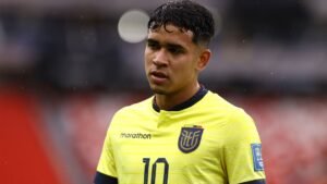 Ecuadoraanse speler in een felgeel shirt met nummer 10, lijkt in gedachten verzonken tijdens een wedstrijd, toont passie voor voetbal.