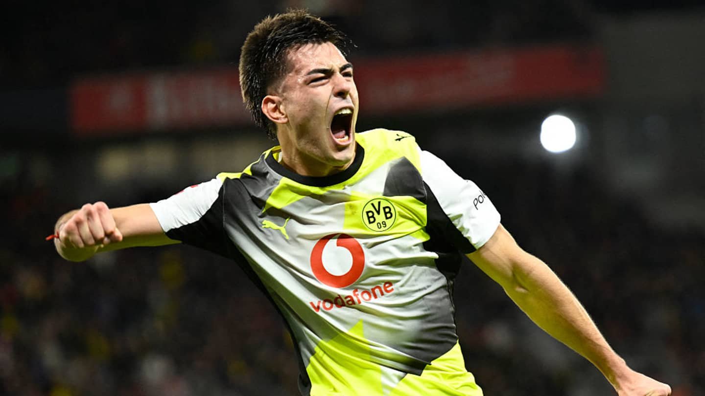 Celebrating Borussia Dortmund player in bright yellow and black kit, expressing excitement after scoring a goal during a match.