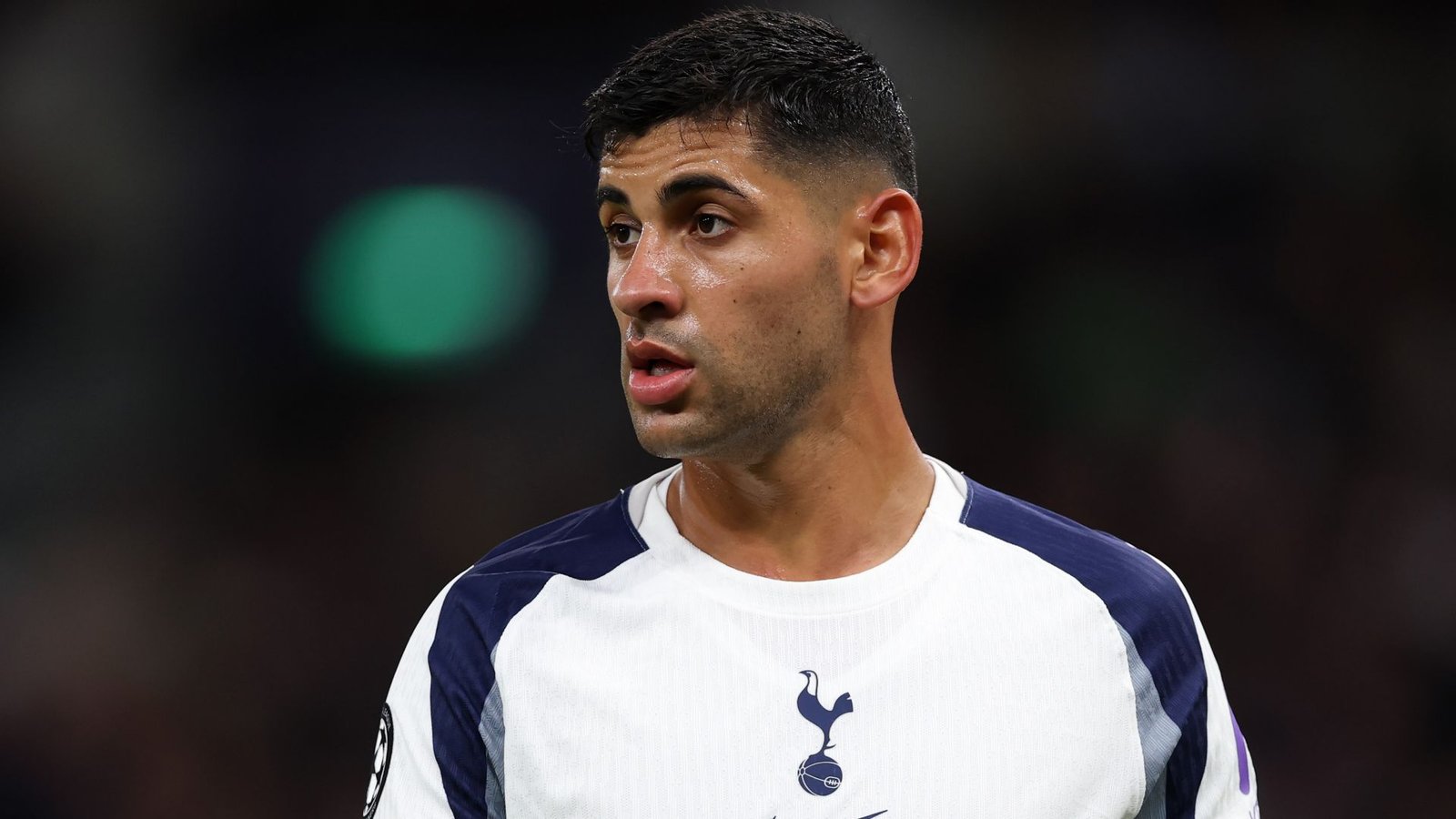 Cristian Romero in een Tottenham Hotspur-tenue, met een intense uitdrukking tijdens een wedstrijd, tegen een wazig stadionachtergrond.