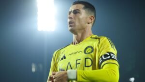 Cristiano Ronaldo, en maillot jaune d'Al Nassr, affiche une détermination alors qu'il se prépare pour un match, les lumières du stade brillant au-dessus de lui.