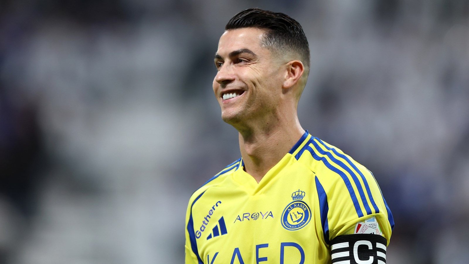 Cristiano Ronaldo glimlacht in een levendig geel Al Nassr-tenue en toont zijn aanvoerdersband tijdens een wedstrijd in de Saoedische Pro League.